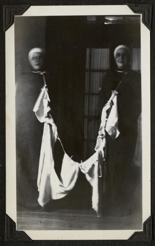 Photo of two students dressed in black, with a clothesline filled with white pieces of clothing draped between them.