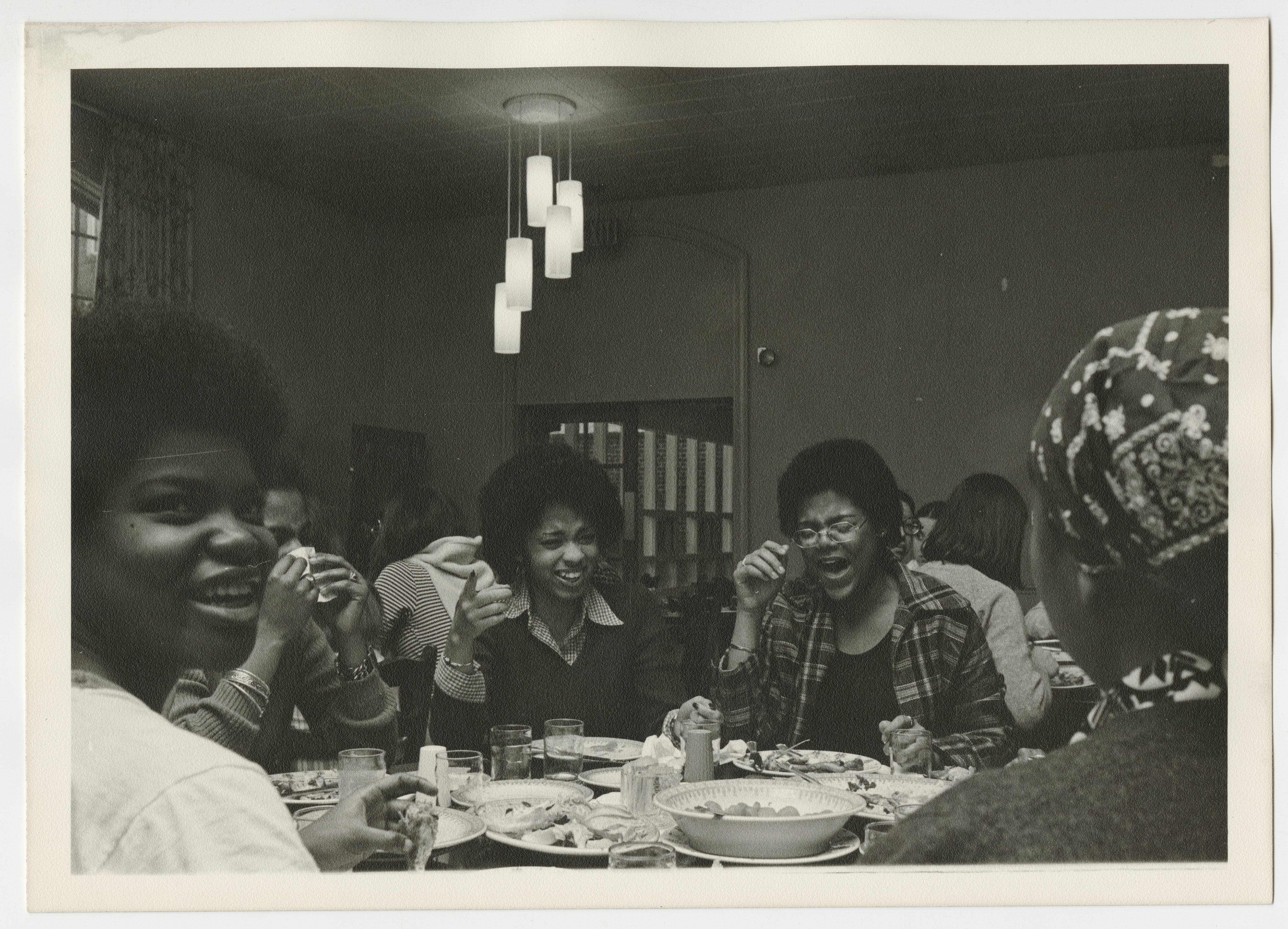 Five Black students at MHC share a laugh around a dining table in a residence hall.